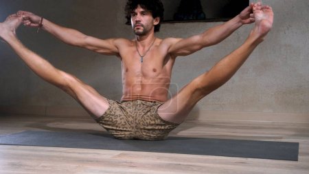 Foto de Un hombre joven y atlético hace yoga y realiza asanas - Imagen libre de derechos