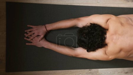 Téléchargez les photos : Vue du dessus d'un jeune homme avec un torse nu lors d'un échauffement avant une séance d'yoga - en image libre de droit