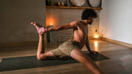 Foto de Un hombre joven y atlético hace yoga y realiza asanas. - Imagen libre de derechos