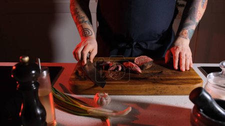 Photo for Slicing beef by a chef on a wooden table. - Royalty Free Image