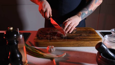 Foto de Cortar carne de res por un chef en una mesa de madera. - Imagen libre de derechos