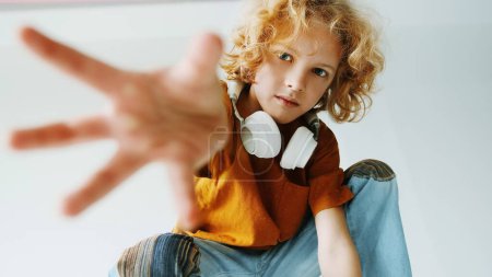 Foto de Niño pequeño extiende la mano hacia adelante, con auriculares. - Imagen libre de derechos