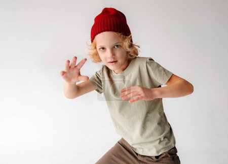 Photo for YounA young male child, wearing a red beanie, is captured mid-jump in the air. His feet are off the ground as he leaps with enthusiasm and energy, showcasing his playful and joyful spirit.g Boy Wearing Red Beanie Jumping in the Air - Royalty Free Image
