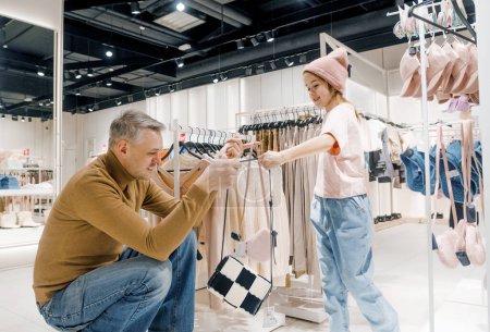 Un père et sa fille explorent et examinent des objets dans un magasin de vêtements moderne, partageant un moment joyeux et ludique ensemble.