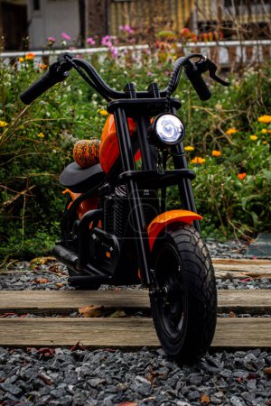Photo for An orange children's eBike, styled like a motorcycle, adorned with a whimsical pumpkin, symbolizing a playful and adventurous autumn ride for young explorers - Royalty Free Image