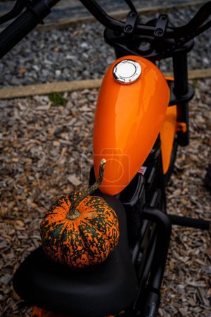 Téléchargez les photos : Un eBike orange pour enfants, stylisé comme une moto, orné d'une citrouille fantaisiste, symbolisant une promenade d'automne ludique et aventureuse pour les jeunes explorateurs - en image libre de droit