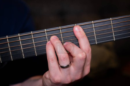 Foto de La mano de un hombre toca con gracia un acorde en la guitarra acústica, tejiendo una melodía armoniosa que resuena con el alma - Imagen libre de derechos