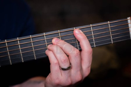 Photo for A man's hand gracefully plays a chord on the acoustic guitar, weaving a harmonious melody that resonates with the soul - Royalty Free Image