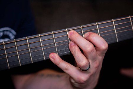 Foto de La mano de un hombre toca con gracia un acorde en la guitarra acústica, tejiendo una melodía armoniosa que resuena con el alma - Imagen libre de derechos