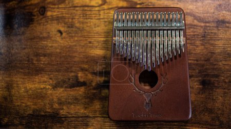 Photo for A Kalimba, the enchanting hand piano, graces a wooden table, inviting musical exploration with its melodic tones - Royalty Free Image