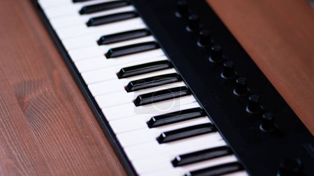 Téléchargez les photos : Un piano MIDI compact sur une table en bois, offrant un espace de travail musical élégant et créatif pour les home studios et les amateurs de musique numérique - en image libre de droit