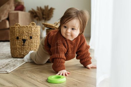 Photo for Toddler child is playing with toys on floor in room. Childhood, kindergarten and development concept. Brown sweater - Royalty Free Image