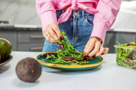 Photo for A woman in a white apron is making a salad in a bowl. the concept of proper nutrition - Royalty Free Image