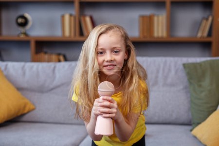 Photo for Preteen child singing into microphone and smile at home, entertainment and education concept, indoor - Royalty Free Image