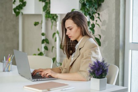 Téléchargez les photos : Femme travaille sur ordinateur portable dans un bureau moderne. Faire rapport d'analyse comptable données d'investissement immobilier, concept de systèmes financiers et fiscaux - en image libre de droit