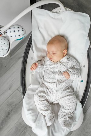 Foto de Adorable baby sleeps in baby swing in room. Newborn concept. - Imagen libre de derechos
