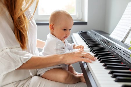 Photo for Mother and baby daughter playing piano. Baby development. Sensory experience. Brain development. Early years. - Royalty Free Image