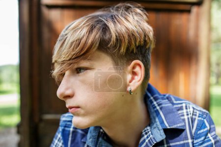 Portrait of serious teenager sitting on grass in park. Gen Z. Unhappy and stress.-stock-photo