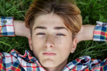 Téléchargez les photos : Portrait d'un adolescent sérieux qui se trouve dans l'herbe et se repose. Gén Z. ! Développement de l'identité. - en image libre de droit