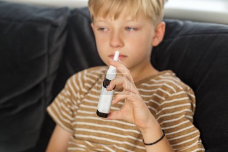 Nasal spray. Seasonal cold. Self-medicating. Health and care concept. Child boy springing medicine in nose against flu.