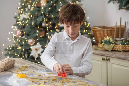 Foto de Niño niño preparar galletas de jengibre para las vacaciones de Navidad y jugar con cortadores de galletas. - Imagen libre de derechos
