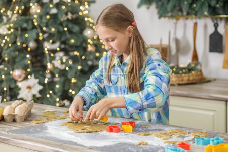 Foto de Niña preparar galletas de jengibre para las vacaciones de Navidad y jugar con los cortadores de galletas. Tiempo de Navidad. - Imagen libre de derechos