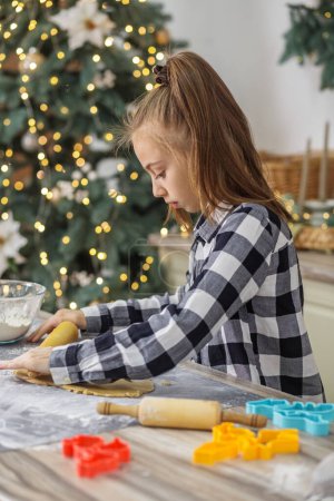 Foto de Niña preparar galletas de jengibre para las vacaciones de Navidad y jugar con los cortadores de galletas. Tiempo de Navidad. - Imagen libre de derechos