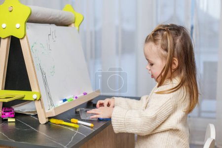 Photo for Early brain development. Toddler girl draws on blackboard at home. - Royalty Free Image