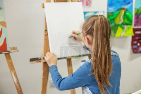 Focused student carefully sketching initial outlines of drawing on blank canvas i