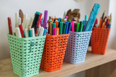 Téléchargez les photos : Un assortiment de marqueurs et stylos colorés organisés en paniers tissés lumineux, prêts à l'emploi dans un cadre de classe créatif - en image libre de droit