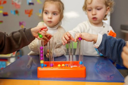 Kleine Kinder im Vorschulalter lernen mit Hilfe von Perlen Zahlen und Farben kennen.