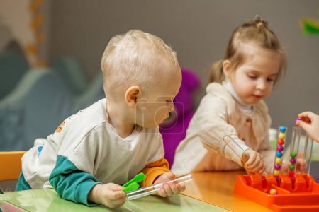 Dos niños pequeños juegan juntos con juguetes educativos coloridos, fomentando el desarrollo temprano y la interacción.