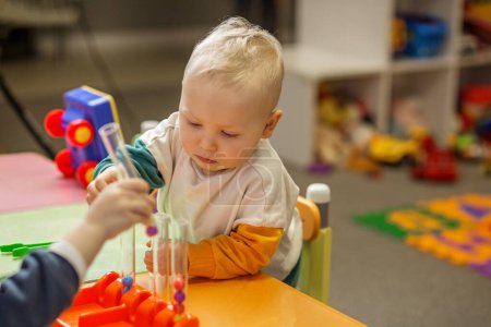 Konzentriertes Kleinkind spielt mit Sortierspielzeug und fördert Feinmotorik im bunten Spielzimmer.