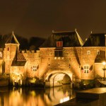 Illuminated medieval monument De Koppelpoort, built in the 14th and 15th centuries, a brick gate with shutters bridging the river Eem at night, Amersfoort, the Netherlands. High quality photo, long