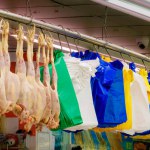 Seven fresh chickens and an assortment of plastic bags in different colors hanging at a poultry market stall at a covered market, London UK. High quality photo