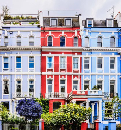 Téléchargez les photos : Rangée avec vue frontale sur trois maisons victoriennes colorées, au printemps avec des arbres en fleurs, Notting Hill, Londres, Royaume-Uni. Photo de haute qualité - en image libre de droit