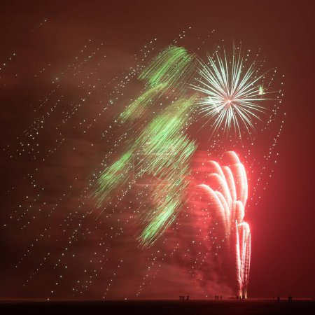 Photo for Fireworks in different colours shooting up high in the sky at the North Sea beach at night, seen from far away at a great distance, New Year, Hook of Holland, the Netherlands. High quality photo - Royalty Free Image