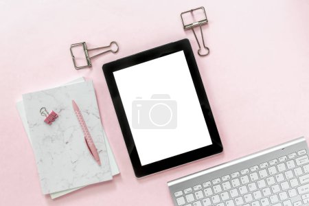 Téléchargez les photos : Pose plate de bureau féminine de la scène de l'espace de travail de bureau avec des articles accessoires de papeterie blanc et argent, y compris le clavier et la souris avec une maquette d'une tablette vierge sur un fond pastel rose clair - en image libre de droit