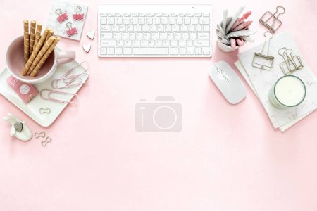 Photo for A feminine woman workspace, with a silver keyboard of a computer on a pastel pink background with copy space. Banner image with candle and other office space and desktop white stationery - Royalty Free Image