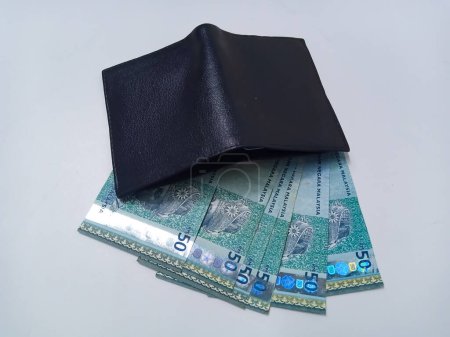 Photo for Black leather wallet with Malaysian Ringgit bank notes isolated on white background. 50 ringgit Malaysian bank notes out of black wallet - Royalty Free Image