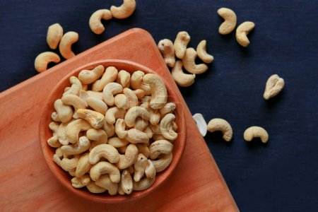 Roasted cashew nuts in a bowl on a wooden background. Healthy food concept.