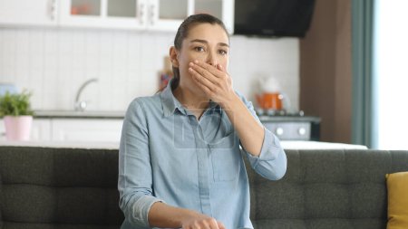 Una joven enferma está tosiendo. Una joven de unos 30 años que tiene dificultad para respirar en la sala de estar de su casa. Dificultad para respirar, asma, dificultad para respirar. Síntomas del virus Corona.