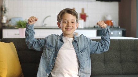 Photo for Little boy shows his arm muscles to the camera.Portrait of little boy showing biceps, muscles, strength to camera at home.Superhero kids game. - Royalty Free Image
