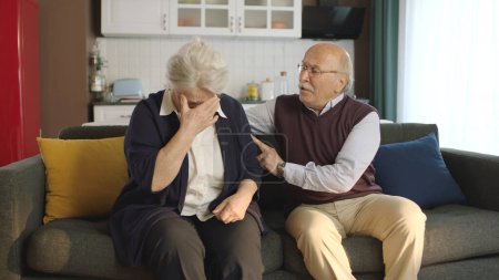 Téléchargez les photos : Un couple âgé assis dans son fauteuil à la maison. Image d'un couple âgé dans des mariages troublés. Vieil homme réconfortant sa femme triste qui pleure. - en image libre de droit