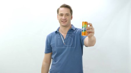 Foto de Istanbul,Turkey-04.22.2022:Man drinks carbonated beverage from metal bottle. Young man drinking Fanta beverage and happy to cool off. Slow motion video. Indoor studio isolated on white background. - Imagen libre de derechos
