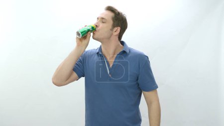 Foto de Istanbul,Turkey-04.22.2022:Man drinks carbonated beverage from metal bottle. Young man drinking sprite beverage and happy to cool off. Slow motion video. Indoor studio isolated on white background. - Imagen libre de derechos