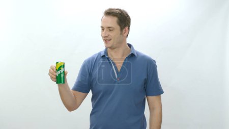 Foto de Man drinks carbonated beverage from metal bottle. Young man drinking sprite beverage and happy to cool off. Slow motion video. Indoor studio isolated on white background. - Imagen libre de derechos
