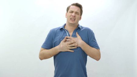 Photo for Sick, unhealthy heart and man with painful cramp in his stomach is squeezing his stomach and suffering from severe heart pain.Man in his 30s strong chest pain,heart attack caused by stress,cardiology. - Royalty Free Image