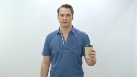 Photo for Studio portrait of young man holding paper coffee mug. Smiling positive man holding paper cup on white background smiling at camera. Portrait of human into coffee. - Royalty Free Image