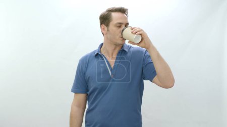 Photo for Studio portrait of young man holding paper coffee mug. Smiling positive man drinking coffee from paper cup on white background. - Royalty Free Image